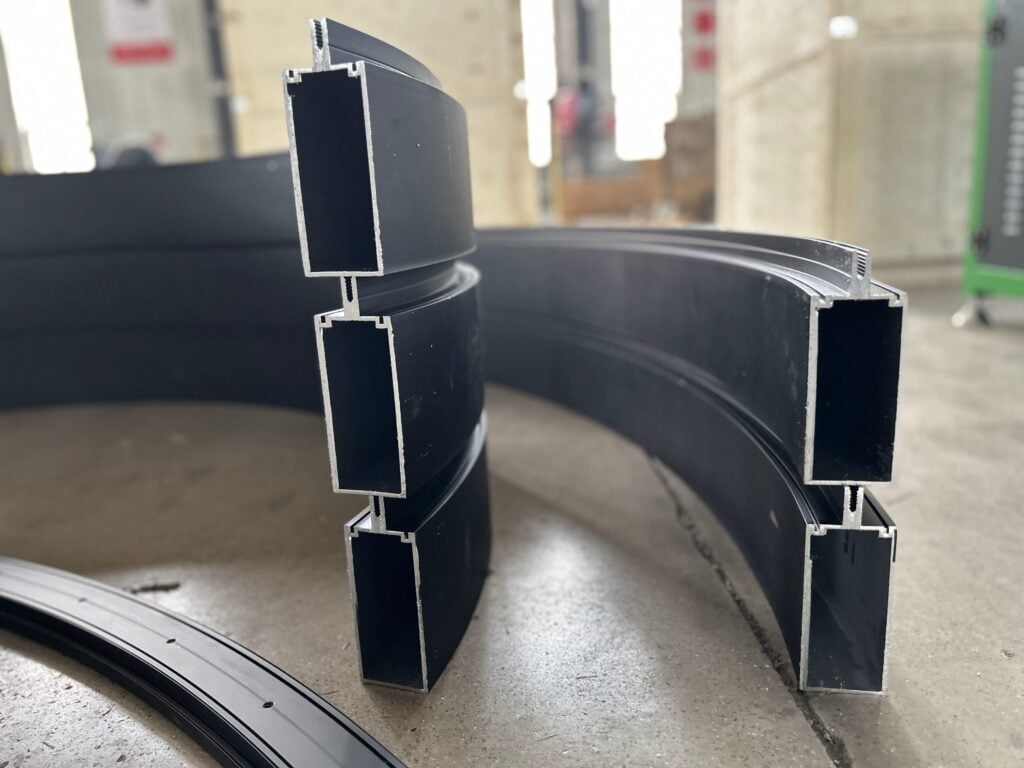 Sección vertical de tres perfiles de aluminio curvados apilados para ventanas y fachadas