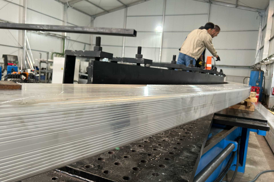 Ingeniero de BIT supervisando a un operador durante el curvado de perfiles de aluminio para carpas y domos
